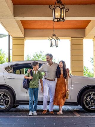 A family stands together by a stylish car, smiling and enjoying a sunny day, exuding warmth and connection.