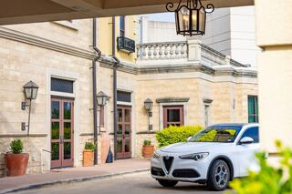 A sleek white SUV parked near an elegant stone building, surrounded by potted plants and classic lanterns, exudes sophistication.