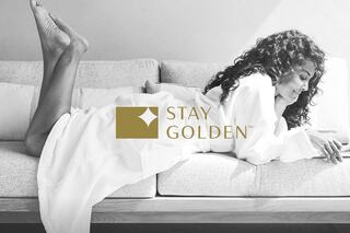 A woman in a cozy setting, dressed in a robe, relaxes on a couch with a thoughtful expression, promoting a message of positivity.