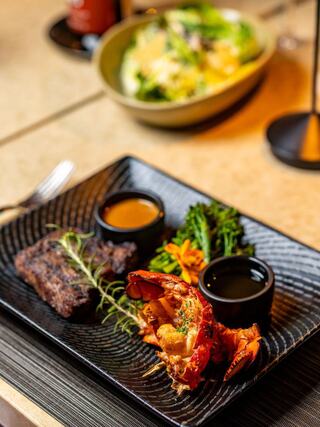 Fluffy pancakes topped with caramelized fruits, served with vibrant drinks and garnished with orchids on a stylish table setting.