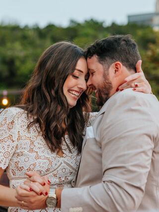 A couple shares a romantic moment, smiling and embracing, surrounded by greenery and soft lighting, radiating joy and love.
