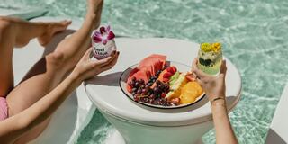 A relaxing poolside scene featuring vibrant fruit and refreshing drinks, perfect for a sunny day. Enjoying leisure and indulgence!