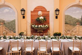 A beautifully decorated table set with greenery and floral arrangements, against a backdrop of elegant murals, creating a charming ambiance.