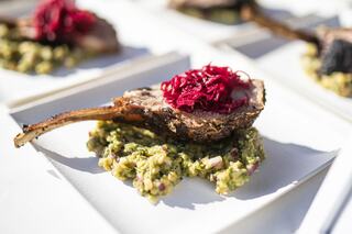 A beautifully plated dish features a juicy lamb chop atop a bed of flavorful green mash, garnished with vibrant pickled beets.