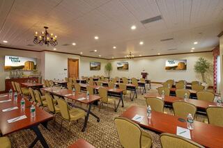 A well-equipped conference room with rows of tables and chairs, reflecting a professional setting, featuring screens and a cozy ambiance.