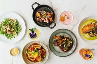 A vibrant spread of gourmet dishes, including seafood, salads, and colorful drinks, elegantly arranged on a polished tabletop.