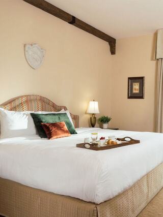 A cozy, well-decorated bedroom features a plush bed with decorative pillows and a tray of snacks and drinks, enhancing the inviting atmosphere.