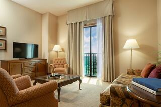 A cozy living space featuring a TV, elegant furniture, ample natural light from floor-to-ceiling windows, and a warm, inviting atmosphere.