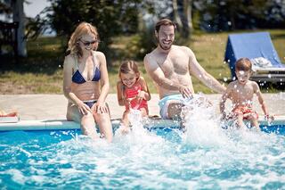 A family enjoys a sunny day by the pool, splashing water and having fun as they spend quality time together.