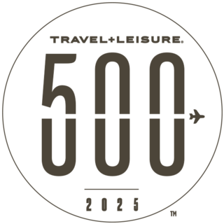 A circular logo featuring "TRAVEL+LEISURE," the number "500," and "2025," with an airplane graphic incorporated into the design.