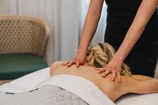 A person receives a calming massage, with hands applying pressure to their back in a serene, spa-like setting.