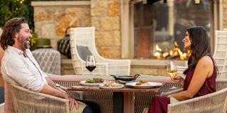 A modern, multi-story hotel with a yellow facade, balconies, surrounded by lush greenery and a winding driveway.