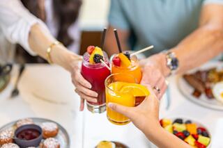 Cheers with colorful drinks in vibrant glasses, surrounded by delicious food, as friends celebrate together in a joyful dining atmosphere.