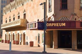 A historic theater exterior features ornate architecture and a marquee displaying "ORPHEUM," showcasing its artistic charm and cultural significance.