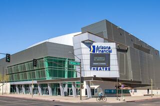 A modern building featuring large glass sections and signage for Arizona Financial Theatre, located on a busy street with traffic signals.